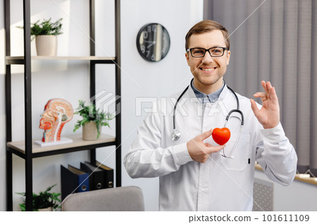 Doctor in white coat and glasses holding a red heart at hospital office. Medical health care and doctor staff service concept 101611109