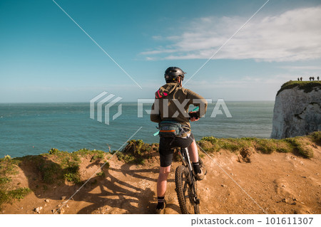 Tourist on the bike watching the Old Harry Rocks in Dorset, Jurrasic coast, Swanage South England. White cliffs. English tourist attraction. Sunny day on the beach 101611307