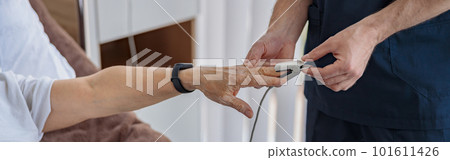 Nurse checking with fingertip pulse oximeter oxygen saturation of patient blood in hospital 101611426