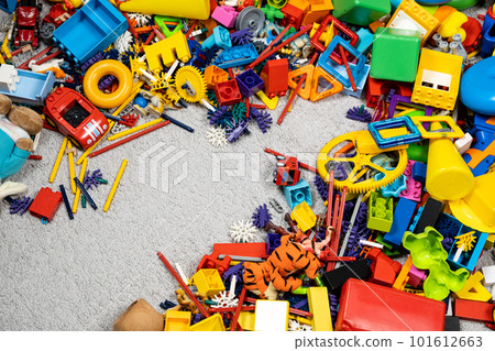 An abundance of toys in the children's room, a lot of plastic multi-colored parts from designers, spare parts for toys, figurines and cubes. An abundance of toys in the children's room, a lot of plastic multi-colored parts from designers, spare parts for toys, figurines and cubes. 101612663