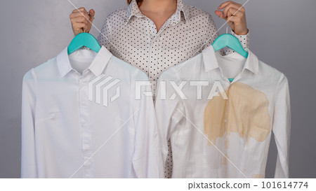 A woman compares two white shirts before and after washing. The girl is holding one blouse, clean and ironed, and the other, dirty with coffee stains A woman compares two white shirts before and after washing. The girl is holding one blouse, clean and ironed, and the other, dirty with coffee stains 101614774
