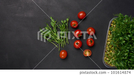 Red tomato and sprouted pea seeds on a black background, microgreens for salad, detox. Top view Red tomato and sprouted pea seeds on a black background, microgreens for salad, detox. Top view 101614874