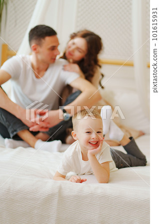 funny little son lies in bed against the background of loving mom and dad funny little son lies in bed against the background of loving mom and dad 101615931