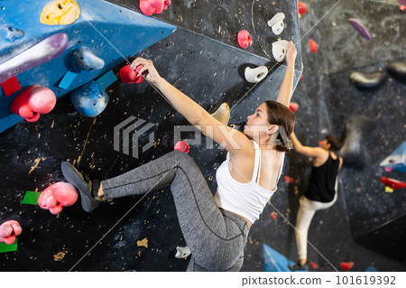 Female fitness climber training at bouldering gym. Young woman rise up on artificial climbing wall 101619392