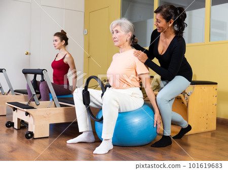 Latin american woman instructor helps to perform exercises with fitness balls and rings Latin american woman instructor helps to perform exercises with fitness balls and rings 101619683