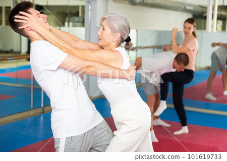 Sportive woman conducts painful reception on the eyes of man in gym. Self defense lessons Sportive woman conducts painful reception on the eyes of man in gym. Self defense lessons 101619733