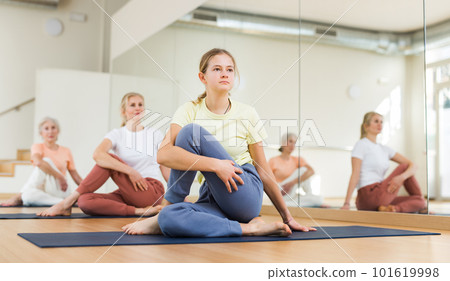 Teenage girl sitting in lord of fisher pose during yoga training 101619998