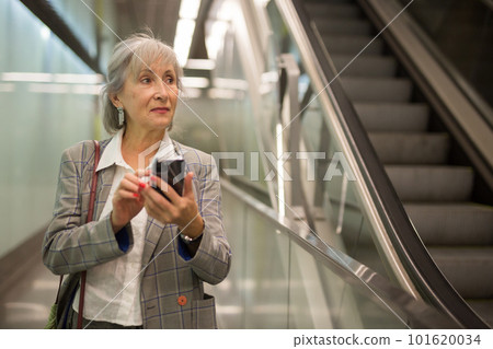 Mature businesswoman using smartphone in office building 101620034