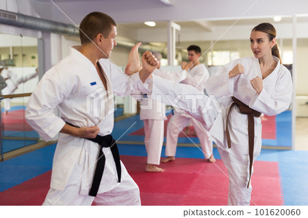 Man and woman in kimono sparring together during karate training Man and woman in kimono sparring together during karate training 101620060