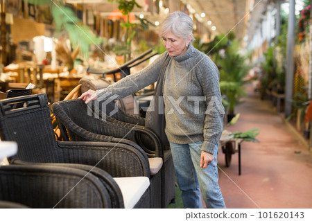 Senior woman looking for plastic rattan garden furniture in store 101620143