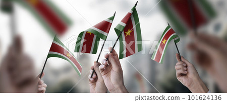A group of people holding small flags of the Suriname in their hands A group of people holding small flags of the Suriname in their hands 101624136