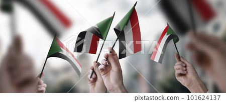 A group of people holding small flags of the Sudan in their hands A group of people holding small flags of the Sudan in their hands 101624137