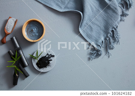 A bird's-eye view of charcoal powder, facial mask and towel on gray background. Text can be added in the blank space A bird's-eye view of charcoal powder, facial mask and towel on gray background. Text can be added in the blank space 101624182