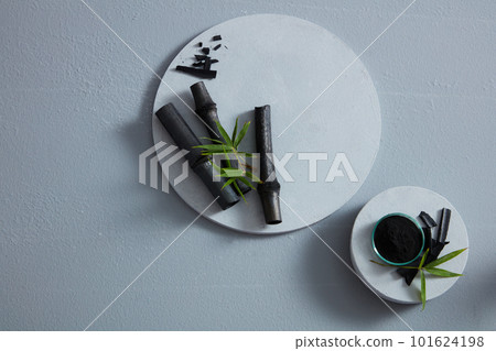 Black bamboo and a bowl of black charcoal powder placed on white podiums with top view. Blank space for advertising, abstract content Black bamboo and a bowl of black charcoal powder placed on white podiums with top view. Blank space for advertising, abstract content 101624198