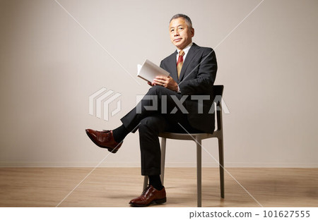 Senior man sitting on a chair with a book Senior man sitting on a chair with a book 101627555