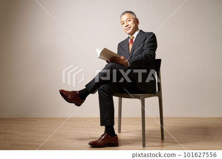 Senior man sitting on a chair with a book 101627556