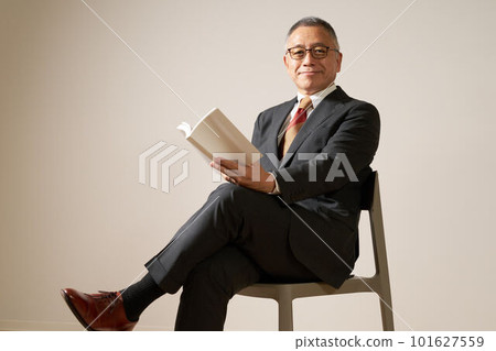 Senior man sitting on a chair with a book 101627559