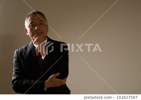 A senior man in a suit touching his chin and turning his gaze Business image 101627567
