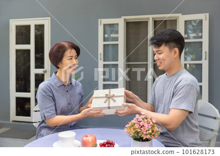 Adult son gives a gift to mom on the mother's day. 101628173