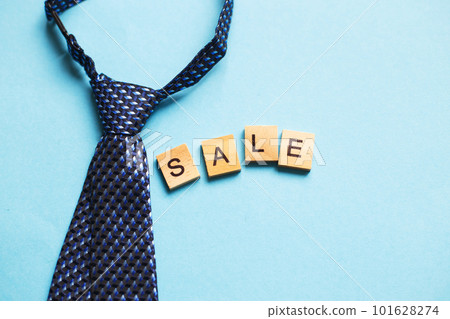 the word sale made by wooden cubes on a blue background with a tie. the word sale made by wooden cubes on a blue background with a tie. 101628274