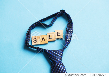the word sale made by wooden cubes on a blue background with a tie. the word sale made by wooden cubes on a blue background with a tie. 101628276