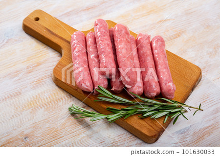 Raw farm sausages with rosemary on wooden table Raw farm sausages with rosemary on wooden table 101630033