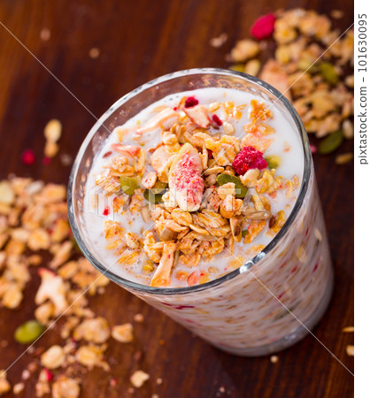 Oatmeal with dried fruit and milk in a glass.  101630095