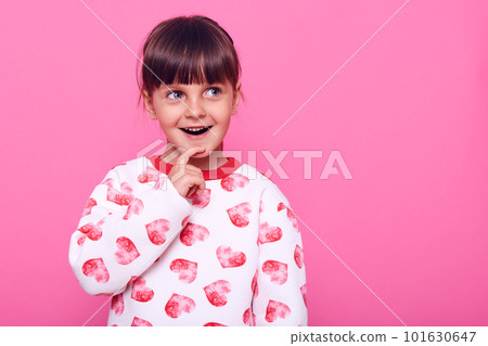 Excited little girl has excellent idea, keeping finger on her chin, looking away with happy expression, copy space for advertisement, isolated over pink background. Excited little girl has excellent idea, keeping finger on her chin, looking away with happy expression, copy space for advertisement, isolated over pink background. 101630647