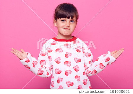 Little sly contented girl with her arms outstretched to the side has cunning expression on her face, being ready to embody her insidious plans in life, isolated over pink background. 101630661