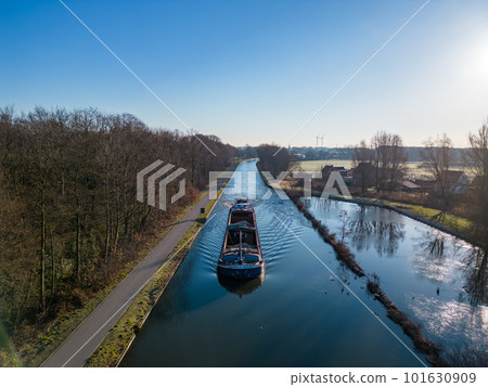 Aerial view of a colourful dramatic sunrise sky over a canal with a cargo boat in Belgium. Canals Aerial view of a colourful dramatic sunrise sky over a canal with a cargo boat in Belgium. Canals 101630909