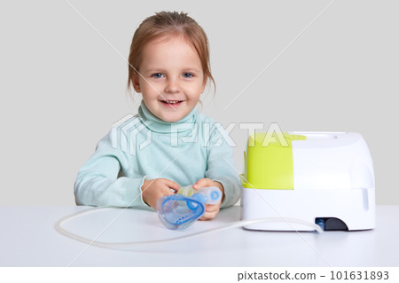 Adorable girl inhales couple containing medication, wants to stop chest coughing, uses inhalor, has medical procedure, asthmatic attack isolated over white background. Home treatment concept. Adorable girl inhales couple containing medication, wants to stop chest coughing, uses inhalor, has medical procedure, asthmatic attack isolated over white background. Home treatment concept. 101631893