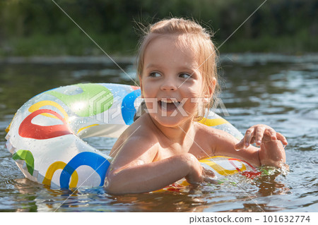 Cheerful playful littl girl swimming with help of swimming circle, opening her mouth widely with excitement, looking aside, grabbing with her hands, enjoying process of swimming. Child activities. Cheerful playful littl girl swimming with help of swimming circle, opening her mouth widely with excitement, looking aside, grabbing with her hands, enjoying process of swimming. Child activities. 101632774