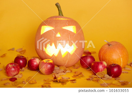 Horizontal shot of harvest or Thanksgiving background with pumpkins, apples and fallen leaves, Jack o'lantern, isolated over yellow studio background. Halloween or seasonal autumnal concept. Horizontal shot of harvest or Thanksgiving background with pumpkins, apples and fallen leaves, Jack o'lantern, isolated over yellow studio background. Halloween or seasonal autumnal concept. 101633055