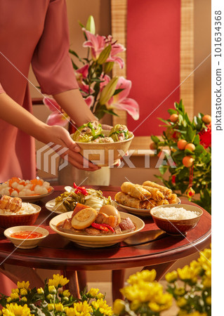 Tet banquet with a hand model holding a bowl of soup. Flowers and Kumquat tree as the background. for holiday food advertising 101634368