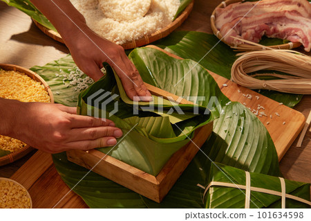 Front view of chef making Chung cake (sticky rice cake) with pork rice and corn in wooden kitchen background. Chinese New Year celebration Front view of chef making Chung cake (sticky rice cake) with pork rice and corn in wooden kitchen background. Chinese New Year celebration 101634598