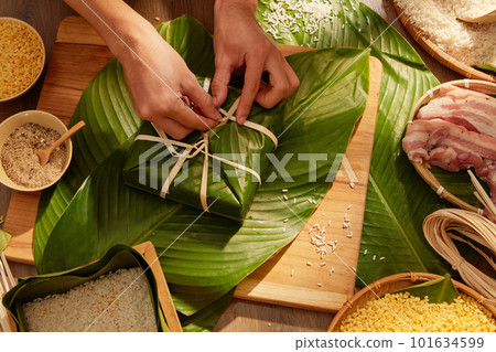 Hands of person making traditional sticky rice cakes for Chinese New Year celebration. All ingredients are placed on a wooden table. Top view Hands of person making traditional sticky rice cakes for Chinese New Year celebration. All ingredients are placed on a wooden table. Top view 101634599
