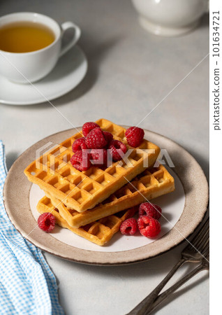 Breakfast waffles with berries in plate served with cup of tea. 101634721