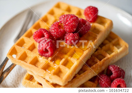 Closeup waffles with berries in plate served with cup of tea. 101634722