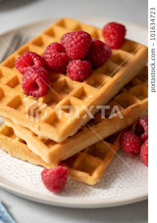 Closeup waffles with berries in plate served with cup of tea. 101634723
