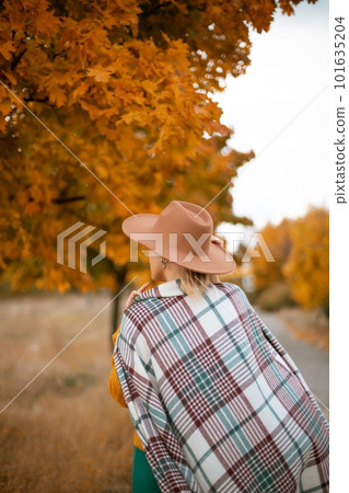 autumn woman in a green dress, brown hat, plaid, against the background of an autumn tree 101635204