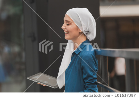 Beautiful muslim girl using digital tablet for communication with friend outdoor Beautiful muslim girl using digital tablet for communication with friend outdoor 101637397