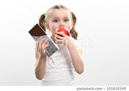 Little cute girl chooses apple over chocolate, preference of healthy food over unhealthy and unhealthy. 101638169