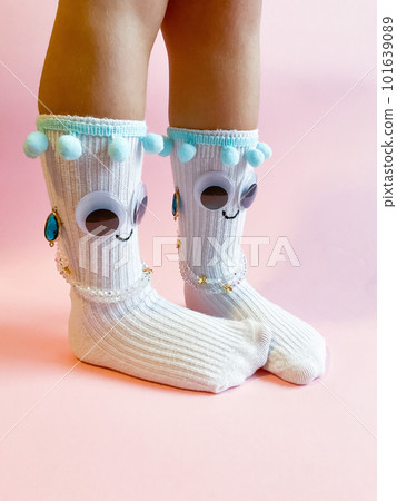 Baby socks with eyes and smile on pink background 101639089