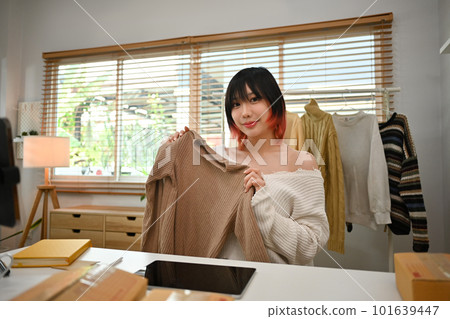 Young female fashion designer standing near clothing rack, working on new womenswear collection in modern studio Young female fashion designer standing near clothing rack, working on new womenswear collection in modern studio 101639447