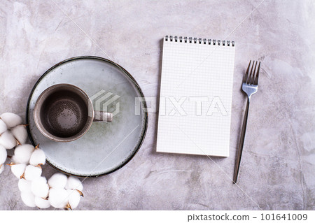 Empty ceramic mug, plate, cotton and blank open notebook on gray background top view Empty ceramic mug, plate, cotton and blank open notebook on gray background top view 101641009