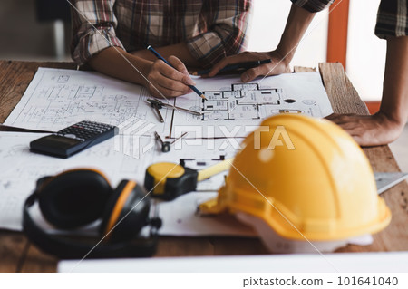 Architect and Engineer working with blueprints for architectural plan, engineer sketching a construction project, green energy concept Architect and Engineer working with blueprints for architectural plan, engineer sketching a construction project, green energy concept 101641040