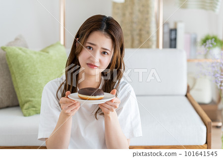 Young woman holding back on donuts 101641545