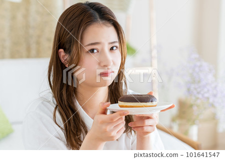 Young woman holding back on donuts 101641547