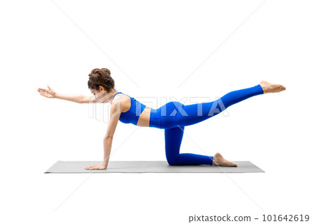 Young fit woman in blue sportswear does bird dog drill with one leg and arm up, isolated on white. 101642619