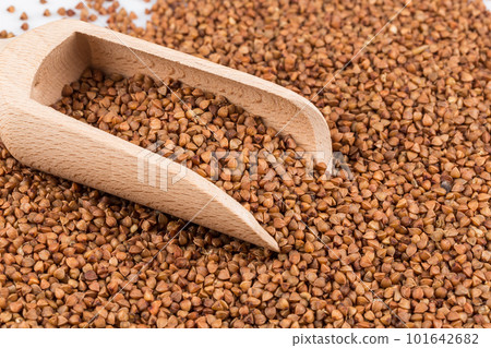 Uncooked buckwheat on wooden spoon 101642682